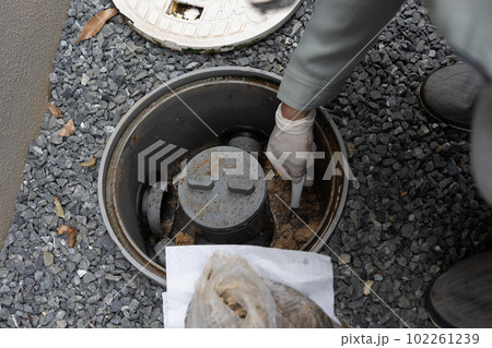 一戸建て住宅の外の汚水桝を掃除しているところ 一戸建て住宅の外の汚水桝を掃除しているところ 102261239
