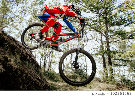 male racer cyclist riding steep descent downhill race in forest, summer mountainbike championship male racer cyclist riding steep descent downhill race in forest, summer mountainbike championship 102261562