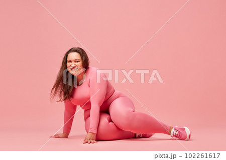 Self-care and well being. Young overweight woman training in sportswear against pink studio background 102261617