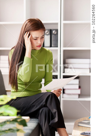 Stressed woman sits on sofa at home, studying and analyze house bills and submitting tax forms. Stressed woman sits on sofa at home, studying and analyze house bills and submitting tax forms. 102264560