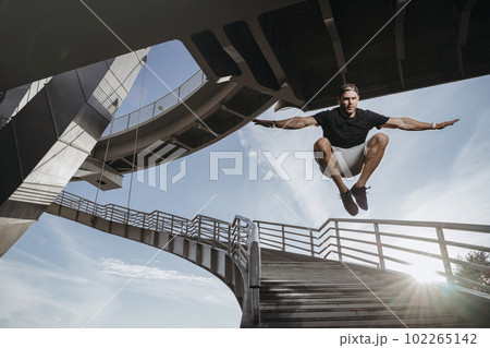 Freerunning athlete doing beautiful jump from bridge 102265142