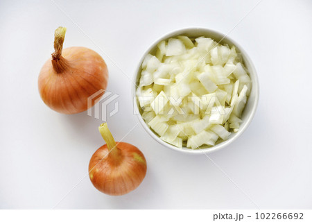Two onions and chopped onion on a white plate. Onion on a white background. Two onions and chopped onion on a white plate. Onion on a white background. 102266692