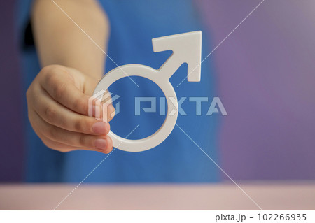The concept of gender. Male gender symbol in hand on purple background with copy space 102266935
