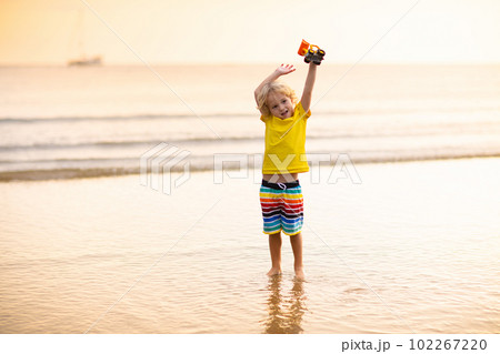 Child playing on ocean beach. Kid at sunset sea. Child playing on ocean beach. Kid at sunset sea. 102267220