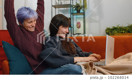 Celebrating Success: Two Lesbian Women Family Couple Use Laptop, Win Triumph, Good News at Home 102268014