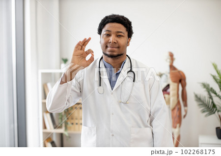 Doctor in lab coat giving okay on clinic background Doctor in lab coat giving okay on clinic background 102268175