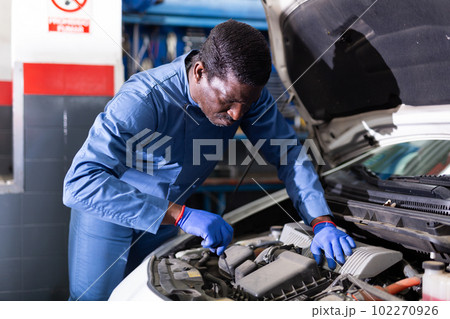 Professional american mechanic man in uniform repairing car engine Professional american mechanic man in uniform repairing car engine 102270926