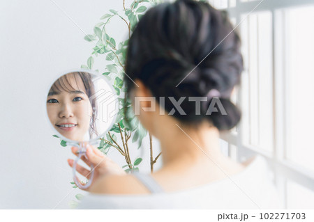 スキンケアをする鏡越しの笑顔のアジア人女性 102271703