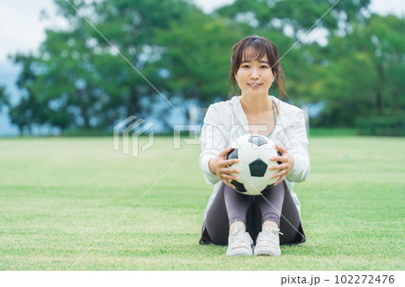 運動場でサッカーボールを持つサッカーファン・サポーターの日本人女性 102272476