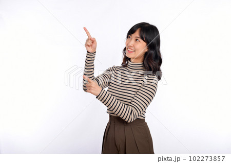 Beautiful young Asian woman on sweater cloth pointing up to copy space and looking at camera with smile face and happy isolated on white background 102273857