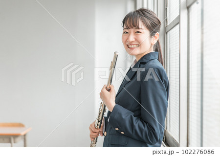 学校の教室でフルートを吹く吹奏楽部のアジア人女子高生 102276086