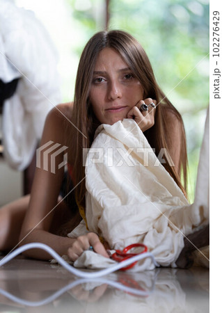 a young fashion designer girl poses next to a mannequin and holds scissors in her hands. a young fashion designer girl poses next to a mannequin and holds scissors in her hands. 102276429