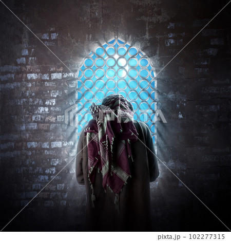 Muslim man with a beard wearing keffiyeh with agal in praying position 102277315