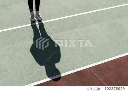 Girl standing on bright sun casting a long shadow Girl standing on bright sun casting a long shadow 102278099