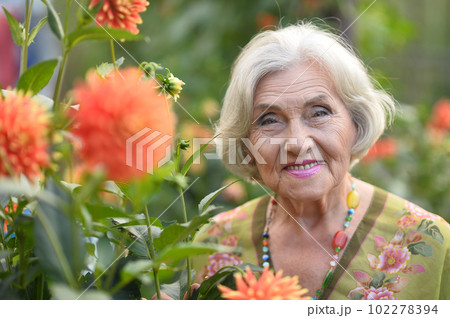 old woman takes care of a flower  102278394