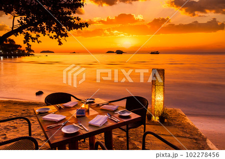 Romantic sunset on the shore of a tropical island. Cafe on the b Romantic sunset on the shore of a tropical island. Cafe on the b 102278456