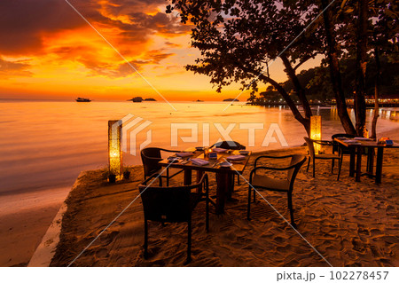 Romantic sunset on the shore of a tropical island. Cafe on the b Romantic sunset on the shore of a tropical island. Cafe on the b 102278457