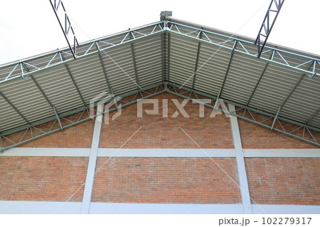 Warehouse roofing built on brick wall facade. 102279317