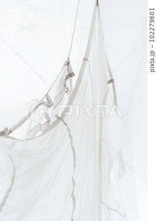 Segment of folded white parachute fabric closeup. Monochrome background with copy space for your design. Segment of folded white parachute fabric closeup. Monochrome background with copy space for your design. 102279601