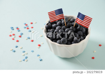 Blueberry decorated American flags in white bowl on blue background. Blueberry decorated American flags in white bowl on blue background. 102279819
