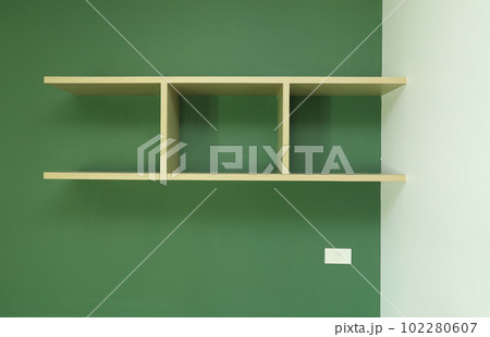 Wooden shelf and white socket installed on green wall 102280607