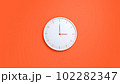Clock on wall. White wall clock isolated on orange background.  102282347