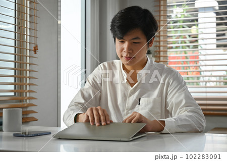 Photo of asian male freelancer opening laptop computer, working on project at home office Photo of asian male freelancer opening laptop computer, working on project at home office 102283091