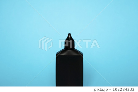 Mock up unbranded black bottle of finish line dry bicycle lubricant with teflon on blue background. Bicycle care, bicycle chain care. 102284232