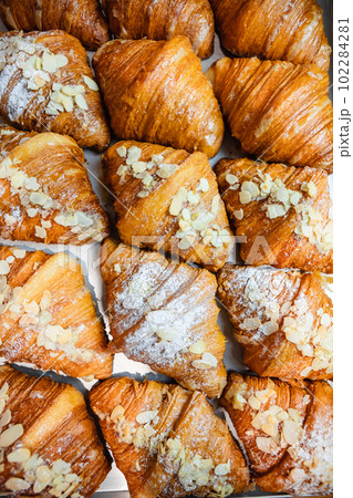 Sprinkle the finished croissants on a baking sheet with almond flakes and powdered sugar 102284281