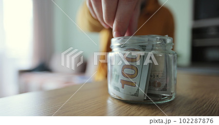 Man hands take out several banknotes of cash from glass jar. The cash in the piggy bank. Man hands take out several banknotes of cash from glass jar. The cash in the piggy bank. 102287876