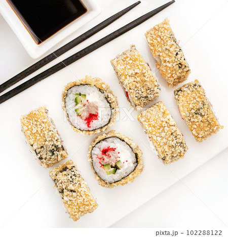 Sushi plate on white background, rolls set breading with tuna on white background from above. Top view of traditional japanese cuisine. Asian food with chopsticks design. 102288122