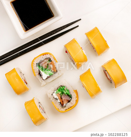 Sushi plate on white background, rolls set with cheese and tuna fish on white background from above. Top view of traditional japanese cuisine. Asian food with chopsticks design. Sushi plate on white background, rolls set with cheese and tuna fish on white background from above. Top view of traditional japanese cuisine. Asian food with chopsticks design. 102288125