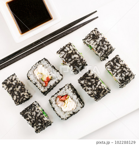 Sushi plate on white background, rolls set with black tobiko egg on white background from above. Top view of traditional japanese cuisine. Asian food with chopsticks design. 102288129