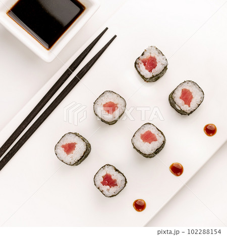 Sushi plate on white background, rolls set with tuna on white background from above. Top view of traditional japanese cuisine. Asian food with chopsticks design. 102288154