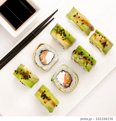 Sushi plate on white background, rolls set with cucumber on white background from above. Top view of traditional japanese cuisine. Asian food with chopsticks design. 102288156