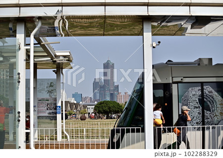 台湾南部高雄市、都市交通機関LRTの西子湾駅、出発した電車と遠くに見える高層ビル、爽やか5月の風景 102288329