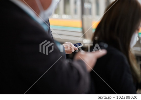 電車待ちの時間でスマホを見ている中年サラリーマンの姿 電車待ちの時間でスマホを見ている中年サラリーマンの姿 102289020
