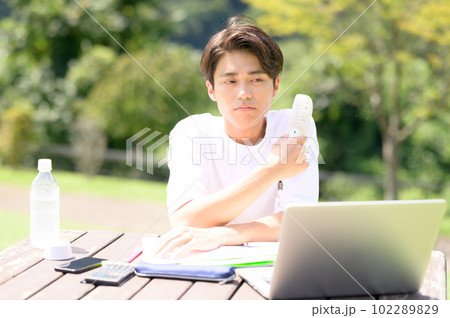 屋外で扇風機を使いながら勉強中の学生 屋外で扇風機を使いながら勉強中の学生 102289829