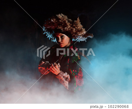 Ukrainian witch - woman in traditional costume with sickle in reeds at night. Ukrainian witch - woman in traditional costume with sickle in reeds at night. 102290068