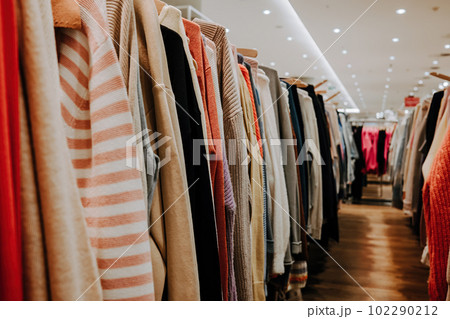 Colorful summer clothes hang on shelf hangers in store. Modern fashion, sale Colorful summer clothes hang on shelf hangers in store. Modern fashion, sale 102290212