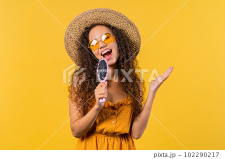 Woman singing, dancing with hair brush instead microphone on yellow background. Woman singing, dancing with hair brush instead microphone on yellow background. 102290217