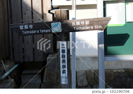 近畿自然歩道に立つ大麻寺と当麻寺駅の方向を示す行先表示板 102290706