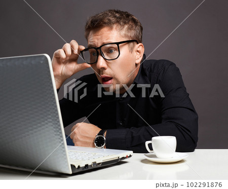 Emotions Man sitting at a computer. funny boy in glasses Emotions Man sitting at a computer. funny boy in glasses 102291876