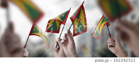 A group of people holding small flags of the Grenada in their hands 102292521