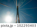 Suspension bridge support cables against a blue sky and sunbeam reflections 102293403