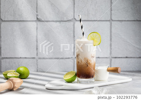 Trendy authentic dirty soda cocktail with cola, lime juice and cream in the kitchen table Trendy authentic dirty soda cocktail with cola, lime juice and cream in the kitchen table 102293776