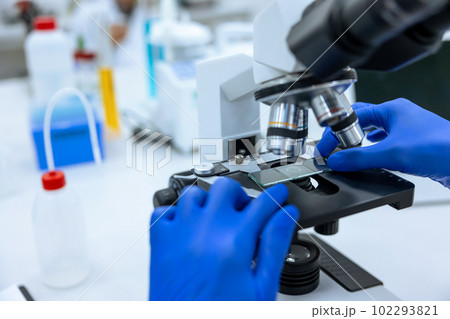 Unrecognizable doctor scientist working in modern laboratory with microscope, genetic researching. 102293821