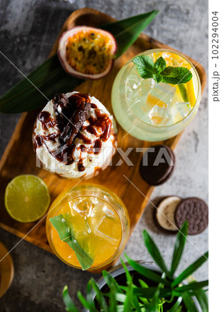 Three cold fruit, coffee and milk cocktails with ice on a grey background. Summer party or bar menu concept 102294004