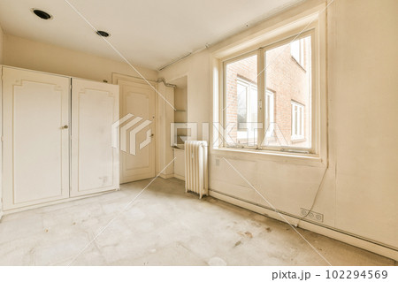 an empty room with white cupboards and cabinets in the corner, looking out onto the street from the window an empty room with white cupboards and cabinets in the corner, looking out onto the street from the window 102294569