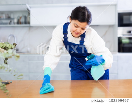 Female cleaning service worker wiping furniture in office kitchen 102299497